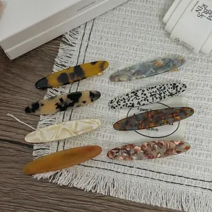 Lot de 8 barrettes à cheveux motifs écaille et marbre sur un fond de tissu blanc doux