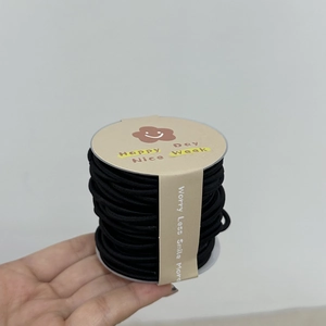 Gros plan d'élastiques à cheveux noirs à haute élasticité sur une bobine blanche