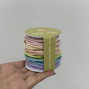 Détail macro d'un ensemble d'élastiques à cheveux multicolores pastel sur bobine blanche