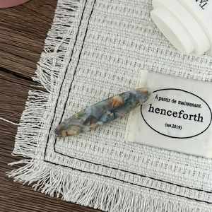Détail d'une pince à cheveux minimaliste avec motif marbré bleu et brun en résine