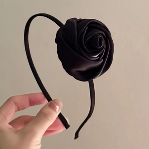 Detail of handcrafted black satin rose headband with silky fabric texture and elegant design