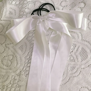 Gros plan de l'élastique à cheveux en satin blanc avec nœud et rubans sur dentelle