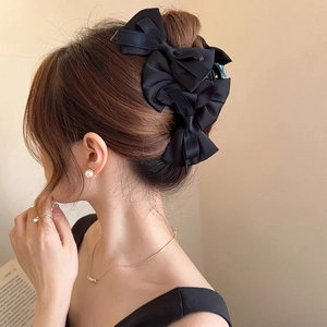 Detail view of large black bow hair claw clip styled on woman's elegant updo