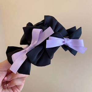 Detail of multi-layered black and purple ribbon bow shark clip with elegant satin texture