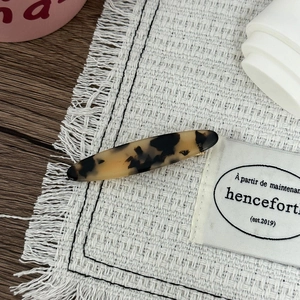 Vue macro détaillée d'une barrette à motif léopard ambré sur un tapis tissé blanc
