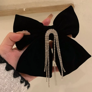 Détail du nœud de cheveux en velours noir avec des pompons en strass argentés