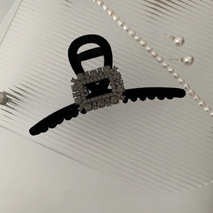 Detail of elegant black velvet hair claw clip with square rhinestone buckle decoration