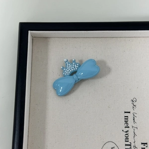 Nahaufnahme einer hellblauen Schleifen-Haarspange mit perlengeschmückter Krone auf Tablett
