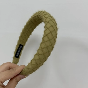 Detailed macro view of green knitted plaid headband with handmade label and fuzzy texture