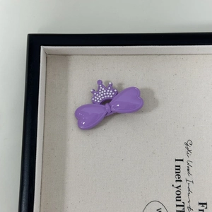 Nahaufnahme einer lila Schleife Haarspange mit Perlenkrone auf weißer Displaytafel