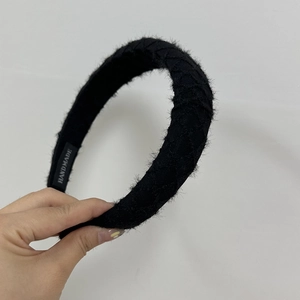 Detailed macro view of black woven hairband featuring the handmade textile label