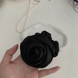 Gros plan d'un chouchou rose en tissu noir avec pétales multicouches à la main
