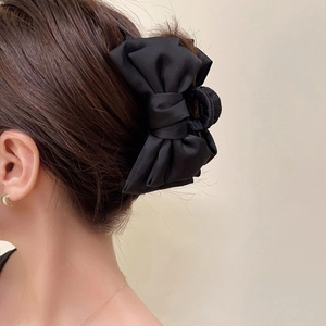 Pince à cheveux élégante avec nœud en satin noir présentée de profil sur modèle