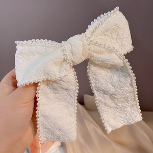 Detailed macro view of the cream white bow headband with pearl trim and floral texture