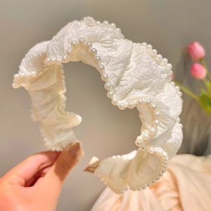 Close-up of cream white ruffled headband with double-row pearl beads and floral details