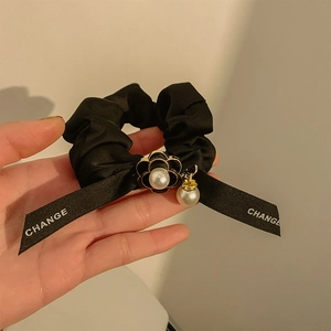 Detail of black satin bow scrunchie with camellia flower and pearl pendant charms