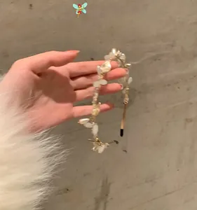 Detail of floral hair band with white pearl petals and beads on gold metal wire