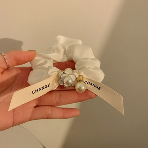 Detail view of white satin scrunchie with pearl charms and camellia flower pendant