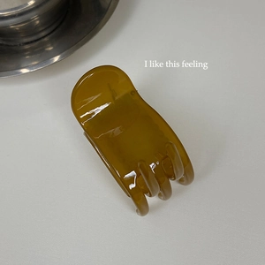 Macro shot of an amber translucent hair claw clip with smooth resin finish on white surface