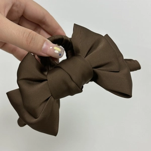 Détail de la pince à cheveux élégante en satin marron foncé avec nœud multicouche