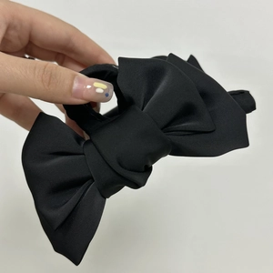 Détail d'une grande pince à cheveux en satin noir à double couche avec texture de soie mate