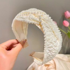 Detail of cream fabric headband with pleated texture and elegant pearl embellishments