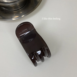 Detailed view of high-gloss dark coffee translucent hair claw with amber texture
