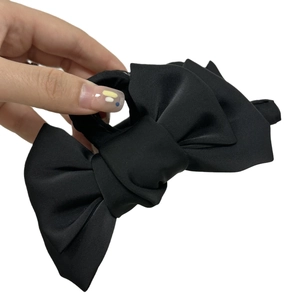 Pince à cheveux élégante avec un grand nœud en satin noir sur un fond blanc neutre