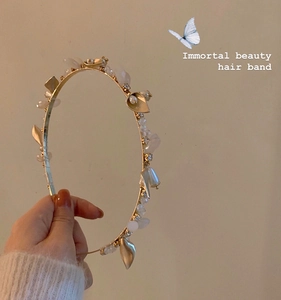 Detailed shot of a gold metal headband with white floral petals and pearl beads