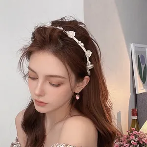 Eleganter Haarreif mit weißen Harzrosen und Perlen, getragen von einem Modell im Wohnambiente