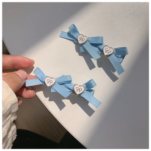Barrette à cheveux nœud bleu ciel avec boucle en métal cœur blanc sur fond blanc