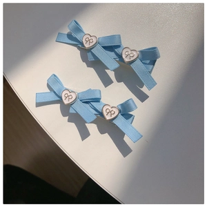Barrettes à nœuds bleu clair avec breloque cœur doré sur un fond blanc épuré