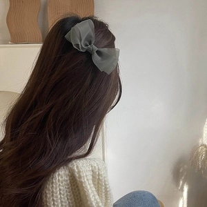 Sage green organza bow hair clip for women styled on long hair in minimalist French design