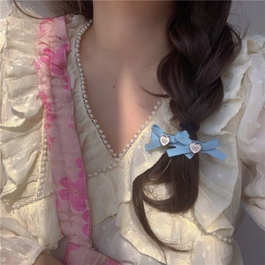 Barrette à cheveux nœud bleu clair avec breloques cœur sur une tresse féminine