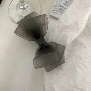 Detailed view of layered dark grey organza bow hair clip with translucent texture