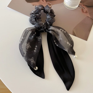 Detail of a black ribbon hair tie with bow design, organza fabric and pearl accents
