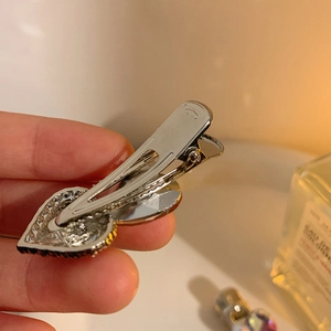 Y2K sparkling rhinestone heart hair clip with silver metal finish and hand-held view