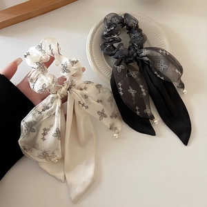 Detail of elegant black and beige bow hair ties with floral print and pearl charms
