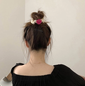 Close-up of rose pink heart charm scrunchie and black hair clip worn on a pony tail