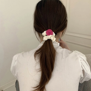 Detail of cream scrunchie with red heart seal on ponytail with white lace top
