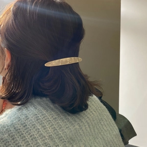 Elegant ivory marble resin hair clip on model with brunette wavy hair in soft light