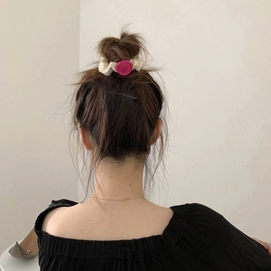 Elegant off-white fabric scrunchie with a magenta heart charm shown on model hair