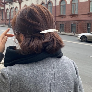 Elegant pearlescent shell pattern hair clip styled on a model in a half-up hair look