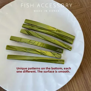 Close-up of six green marbled resin hair clips with unique fluid patterns on a white plate