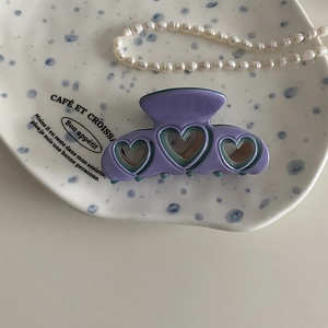 Detalle de pinza para el cabello en acetato lavanda con diseño de corazón hueco en plato