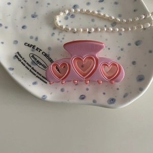 Detalle de pinza de pelo rosa con forma de corazón sobre bandeja decorativa blanca