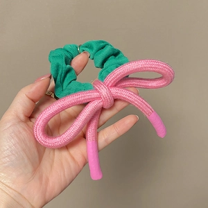 Vue détaillée du grand nœud en tissu rose et du chouchou élastique vert