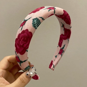 Detailed macro view of pink fabric headband with red rose pattern and leaf design