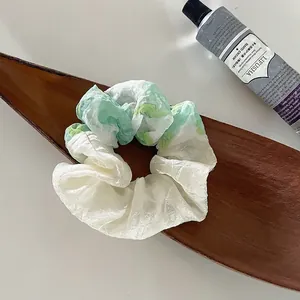 Detailansicht eines Batik-Haargummis aus Seide auf einem dekorativen Holztablett