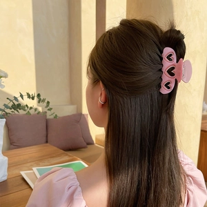 Pinza para el pelo rosa de acetato con forma de corazón en un peinado de modelo